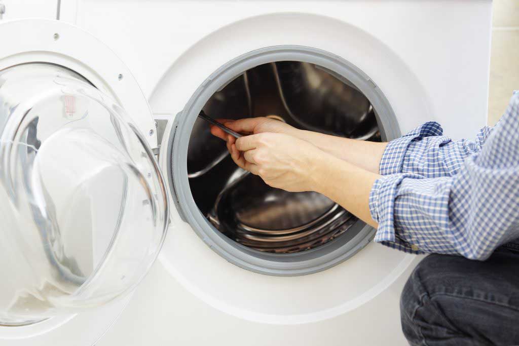 An appliance repair technician working on a front loading washer/dryer
