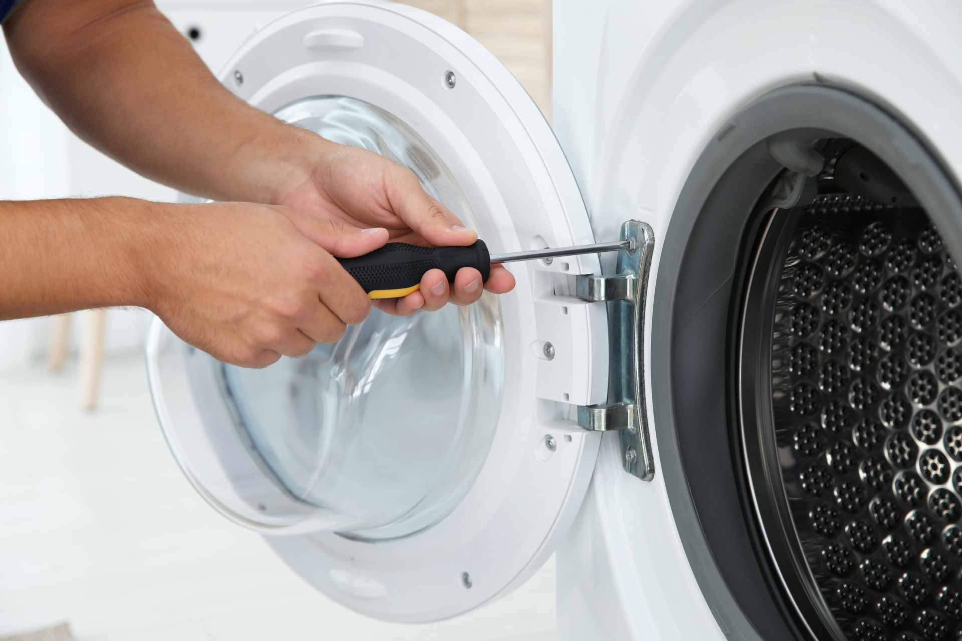 Close up on hands using a screwdriver to fasten the door on a washer/dryer